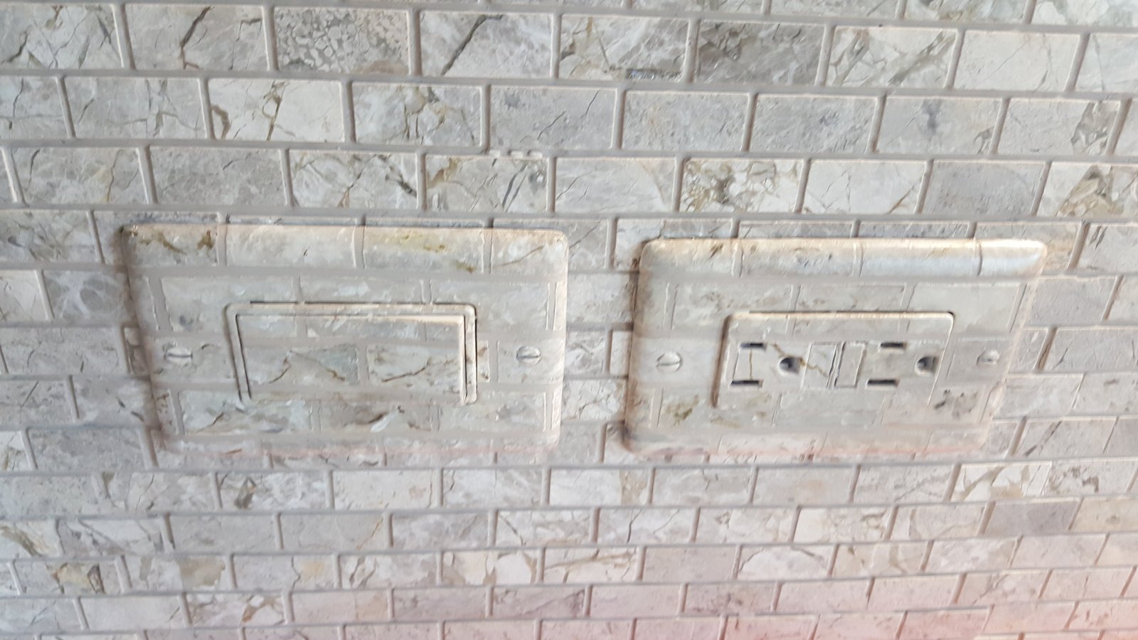 Switch plate faux finished to match the marbled tiles of this backsplash to hide them nicely.